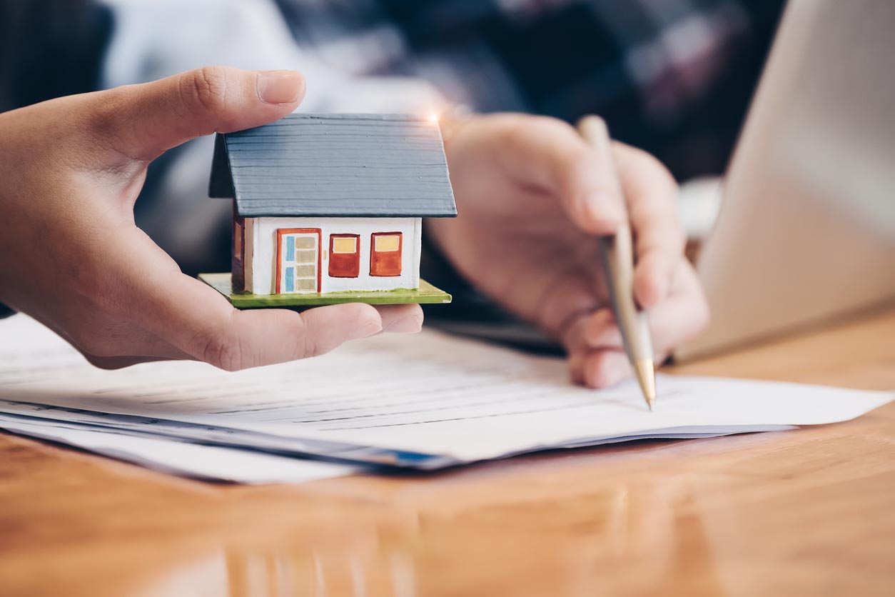 Homme signe un contrat avec une petite maison dans la main