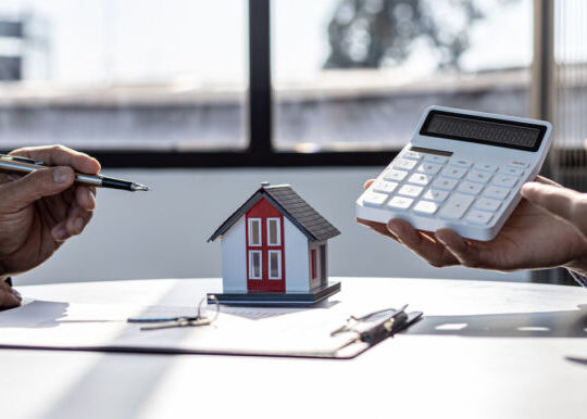 deux hommes à un bureau font un calcul à propos d'une maison